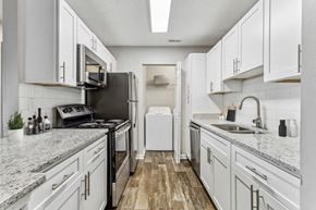 Jonesboro apartment for rent - Luxury Apartments in Jonesboro, GA - The Park at Tara Lake - A Kitchen With White Cabinets, Granite Countertops, Stainless Steel Appliances, Subway Tile Backsplash, and a Double Sink.
