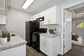 Glendale apartment for rent - Model Kitchen with White Cabinets and Wood-Style Flooring with Bedroom Entrance at Stillwater Apartments in Glendale, AZ.