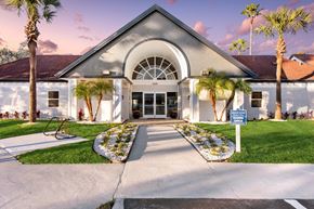 Jacksonville apartment for rent - the front of a building with palm trees and a blue and white sign