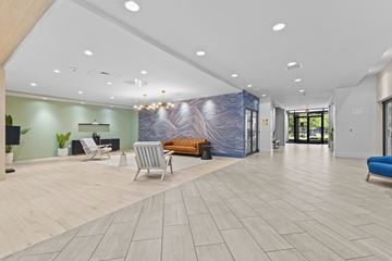 Alexandria apartment for rent - A spacious lobby with a blue and white abstract wall art, a wooden bench, and a blue sofa.
