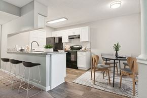 Charlotte apartment for rent - Model Dining Room and Kitchen with Wood-Style Flooring and White Cabinets at Park 2300 Apartments in Charlotte, NC.