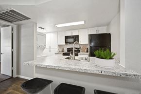 Mesa apartment for rent - Model Kitchen with Wood-Style Flooring, White Cabinets and Washer/Dryer at Country Club Verandas Apartments located in Mesa, AZ.