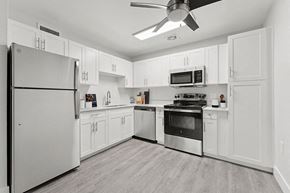 Walnut Creek apartment for rent - 1-Bedroom Apartments in Walnut Creek, CA - The Grove at Walnut Creek - White Kitchen With Quartz Countertops, Stainless Steel Appliances, Wood-Style Flooring, and Ceiling Fan.
