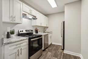 Marietta apartment for rent - Pet-Friendly Apartments in Marietta, GA - The Park on Windy Hill - A Kitchen Features White Shaker Cabinets, Marble-Look Countertops, Stainless Steel Stove, And A Refrigerator.