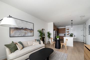 Aurora apartment for rent - A modern living room with a white sofa, a black coffee table, and a painting on the wall.