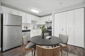 Marshfield apartment for rent - Apartments in Marshfield, MA - Village At Marshfield - Kitchen With White Cabinets, Stainless Steel Appliances, Round Dining Table, And Wood-Style Flooring.