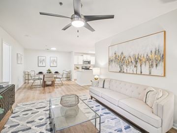 Apex apartment for rent - A living room with a white couch, a glass coffee table, and a painting on the wall.