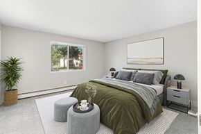 Marshfield apartment for rent - 1-Bedroom Apartments in Marshfield, MA - Village At Marshfield - Bright Bedroom With Plush Carpet, Large Window, Neutral Walls, And Cozy Bed With Nightstands And Modern Lamps.