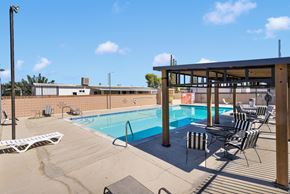 Victorville apartment for rent - A pool with chairs and a building in the background.