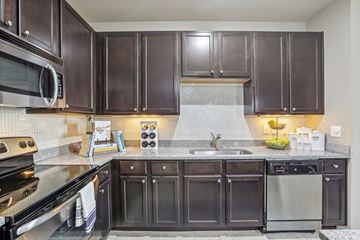 Tampa apartment for rent - A kitchen with dark brown cabinets and stainless steel appliances.