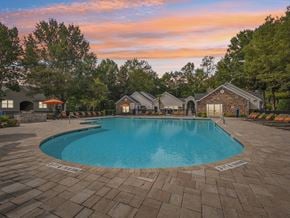 Apex apartment for rent - A large swimming pool surrounded by a brick patio and lounge chairs.