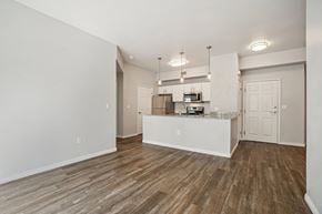 Salt Lake City apartment for rent - Model Living Room and Kitchen with Wood-Style Flooring at Altitude on Fifth Apartments located in Salt Lake City, UT.