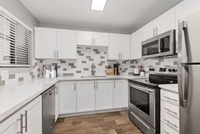 Surprise apartment for rent - 2-Bedroom Modern Apartments in Surprise, AZ - Harmony at Surprise - A Kitchen With White Cabinets, Mosaic Tile Backsplash, Stainless Steel Refrigerator, And Stove.