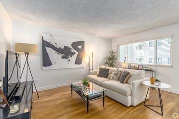 San Diego apartment for rent - A living room with a white couch, a coffee table, and a large abstract painting on the wall.
