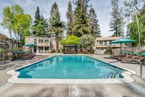 San Jose apartment for rent - Pet-Friendly Affordable Apartments in San Jose, CA - Los Gatos Landing - A Swimming Pool With Lounge Chairs, Large Umbrellas, And Apartment Buildings.