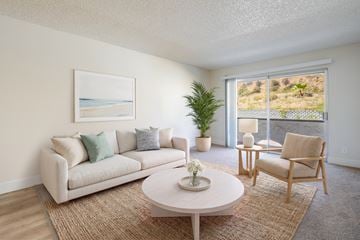 San Diego apartment for rent - A living room with a couch, chair, and a painting of a beach scene on the wall.