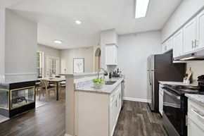 Lawrenceville apartment for rent - Two-Bedroom Apartments in Lawrenceville, GA - Parc at 980 - Open Kitchen With White Cabinets, Granite Peninsula Seating, Stainless Steel Refrigerator, Black Range, And Adjacent Dining Area.