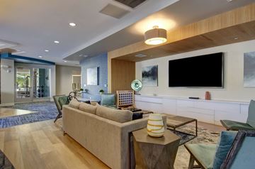 Watertown apartment for rent - A modern living room with a large couch and a flat screen TV mounted on the wall.