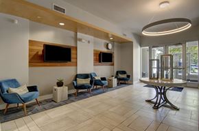 Watertown apartment for rent - A spacious waiting area with blue chairs and a television mounted on the wall.
