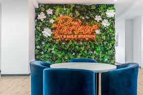 Aurora apartment for rent - A green wall with flowers and the words "The Parker at Smile Station" written in neon.
