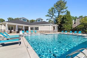 Raleigh apartment for rent - Raleigh, NC, Pet-Friendly Apartments - Bridges at North Hills - A Swimming Pool With A Spacious Sun Deck, Lounge Chairs, Trees, And A Clubhouse Building.