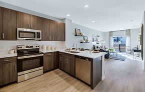 Glendale apartment for rent - Westgate, AZ, Apartments With In-Unit Washer and Dryer - Glen 91 - A Kitchen Features Dark Wood Cabinets, Stainless Steel Stove And Microwave, White Island With Sink And Dishwasher.