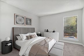 Raleigh apartment for rent - One-Bedroom Apartments in Raleigh, NC - Bridges at North Hills - A Bedroom With Carpet Flooring, A Large Bed, Matching Nightstands, Framed Wall Art, A Dresser, And A Large Window.