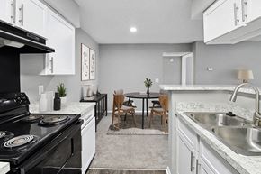 Antioch apartment for rent - Model Kitchen with White Cabinets, Wood-Style Flooring and View of Dining Room at Abbington Heights Apartments in Antioch, TN.