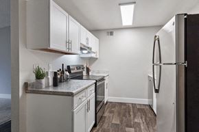 Federal Way apartment for rent - Dog-Friendly Apartments in Federal Way, WA - Sunset Three Twenty - A Kitchen With White Cabinets, Gray Countertops, Stainless Steel Refrigerator, And Stove.