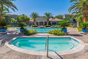 North Las Vegas apartment for rent - North Las Vegas, NV, Apartments Near Las Vegas Strip - Azure Apartment Homes - Swimming Pool And Spa With Palm Trees, Lounge Chairs, And Clubhouse Courtyard Under Blue Sky.