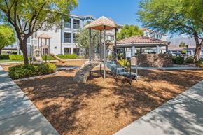 North Las Vegas apartment for rent - A playground with a swing set and a slide in the foreground and apartment buildings in the background.