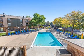 Lakewood apartment for rent - A swimming pool surrounded by blue chairs and apartment buildings.