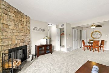 Lakewood apartment for rent - A living room with a stone fireplace and a dining table with chairs.