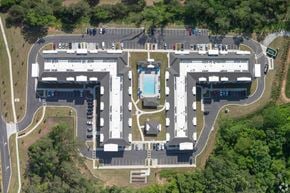 Conyers apartment for rent - An aerial view of a parking lot and buildings with a pool in the middle.