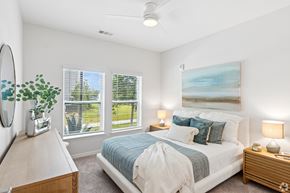 Cocoa apartment for rent - A bedroom with a bed, nightstand, and a painting on the wall.