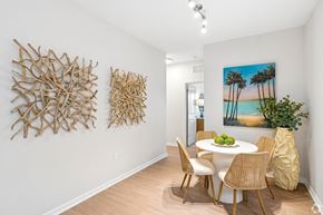 Cocoa apartment for rent - A dining room with a white table and chairs, a painting of a beach scene, and two pieces of artwork on the wall.