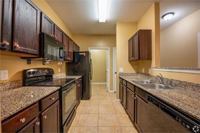 Dade City apartment for rent - A kitchen with brown cabinets and black appliances.