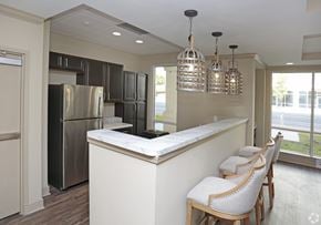 Gainesville apartment for rent - A kitchen with a refrigerator, bar stools, and pendant lights at Arbours at Tumblin Creek ~ Active 55+ Adult Community, 32608