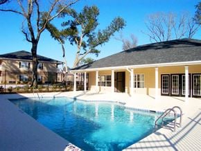 Pensacola apartment for rent - A swimming pool in front of a house with a tree at Arbours at Ensley Apartments, Pensacola