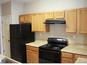 Pensacola apartment for rent - A kitchen with wooden cabinets and black appliances at Arbours at Ensley Apartments, Pensacola, Florida