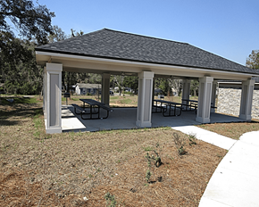 Alachua apartment for rent - A pavilion with a black roof and white pillars is surrounded by a grassy area with a few small plants.