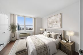 Jersey City apartment for rent - A bedroom with a large bed and a view of the ocean.