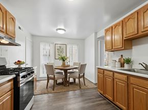 Frederick apartment for rent - A kitchen with wooden cabinets and a table set for four.
