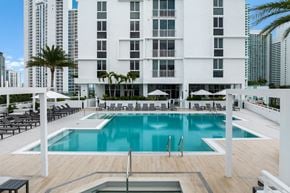 Miami apartment for rent - a large swimming pool in front of a tall building