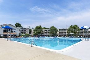 Pikesville apartment for rent - a swimming pool with umbrellas and buildings in the background at Copper and Quarry Village, Pikesville