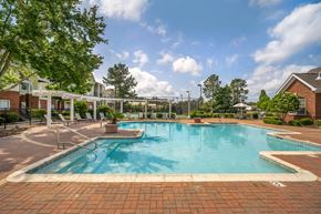 Slidell apartment for rent - A large outdoor swimming pool surrounded by a brick patio.