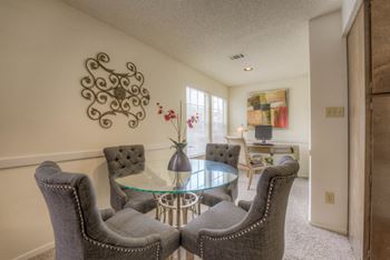 A living room with a glass table and grey chairs
