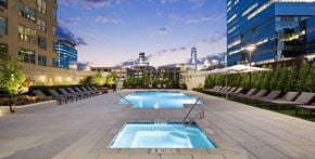 Jersey City apartment for rent - A large swimming pool surrounded by lounge chairs and umbrellas.