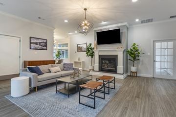 Reston apartment for rent - A modern living room with a grey couch, a fireplace, and a television mounted above it.
