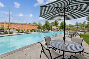 Chatham apartment for rent - A table and chairs set up under an umbrella by a pool.